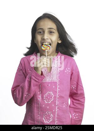 South Asian Indian girl sucking lollipop in nursery school MR Stock