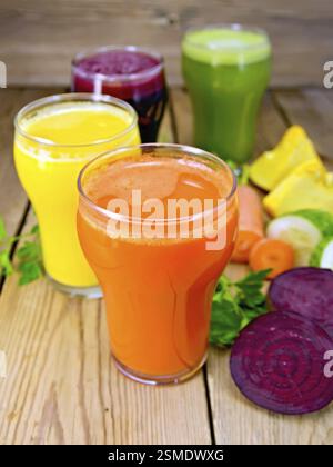 Four tall glass juice from carrot, cucumber, beetroot and pumpkin, vegetables on background of wooden boards Stock Photo