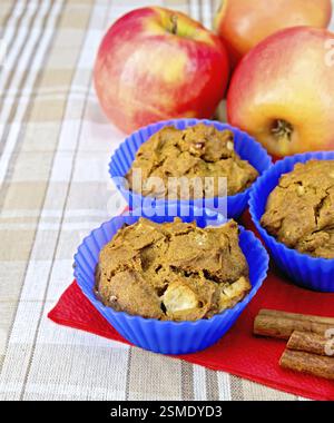 Cupcakes rye with apple in silicone molds on red paper napkin, apples and cinnamon on a background of a linen tablecloth Stock Photo