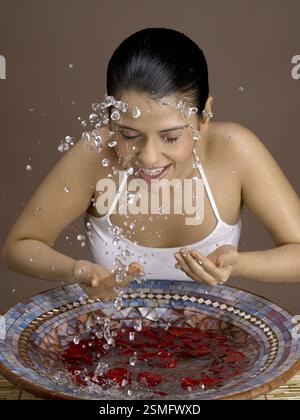 South Asian Indian woman splashing rose petals water on her face MR # 702 Stock Photo
