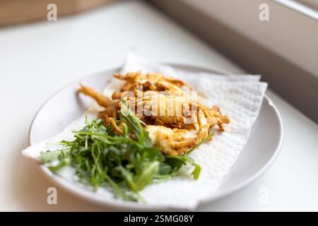 Plate of food with crab cakes and greens on a napkin. The crab cakes are on top of the greens, which are arranged in a neat and appetizing manner Stock Photo
