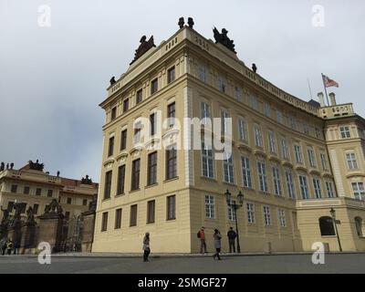 Old Royal Palace, Prague Castle. Yellow building with ornate windows and statues. Tourists exploring the historic site. Czech Republic. A symbol of Cz Stock Photo