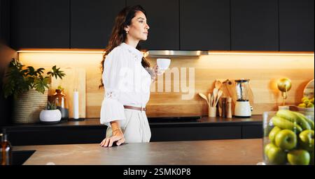 Morning, confident and woman with coffee, kitchen and thinking for business in home, mug and serious. Contemplating, entrepreneur and person with tea Stock Photo