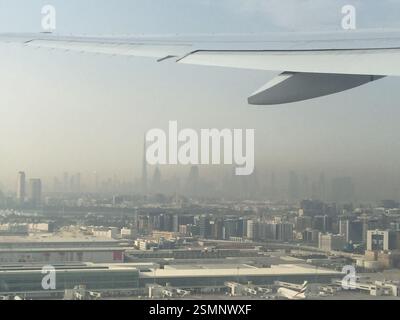 A glimpse of Dubai's urban sprawl unfolds beneath the airplane wing, a miniature world seen from a traveler's perspective. Gazing out the window, one Stock Photo