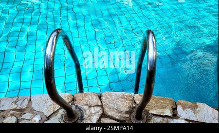 Handrail in a bright blue swimming pool Stock Photo