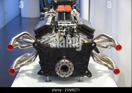 A black model of a V12 engine with multiple exhaust pipes is on display. This powerful engine could be from a collectible model car or a real car. In Stock Photo