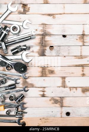 Assorted tools including wrenches and sockets arranged on a rustic wooden surface in a workshop setting Stock Photo