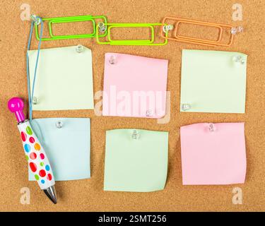 Colorful sticky notes and a pen displayed on a cork board in a creative workspace setting Stock Photo