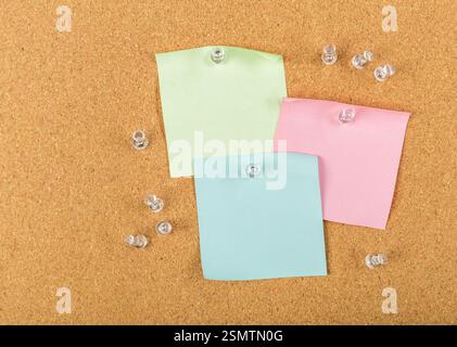 Colorful sticky notes pinned on corkboard surface with clear push pins scattered around Stock Photo