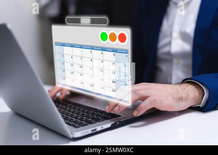 Businessman using a laptop with calendar app on the screen in office Stock Photo