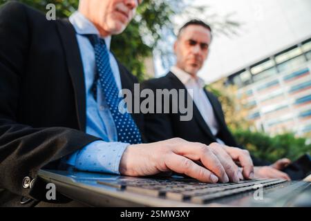 Close up portrait of the hands of a businessman typing on a laptop. Two Professional Businessmen Engaged in Focused Work Collaborating and Productivity Between Mature Males in a Business Context. High quality photo Stock Photo