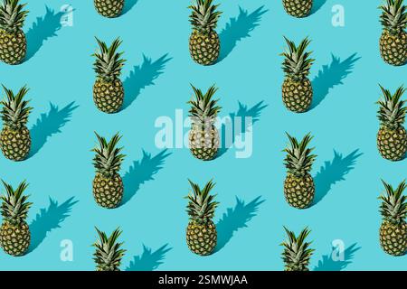 Trendy sunlight summer fruit pattern made of pineapples on light blue background. Nature summer concept. Ananas backdrop idea image. Stock Photo