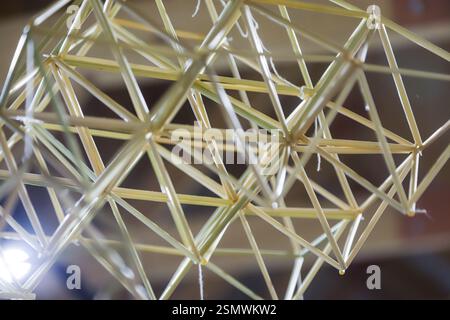 Participants construct a geometric model using toothpicks and strings, engaging in a creative and educational activity within a bright workspace setti Stock Photo