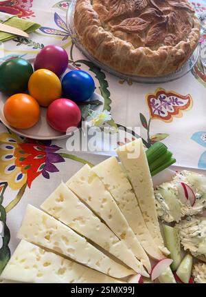 Traditional Easter food. Easter savory pie, Olivier salad, Easter eggs, appetizer, cheese. Family gathering concept. Directly above. Stock Photo
