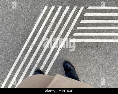 High angle view of woman's boots at pedestrian crossing marking Stock Photo