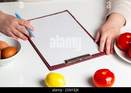 Healthy food planning concept. Mock up of diet plan. Woman creating diet menu for weight loss. Stock Photo