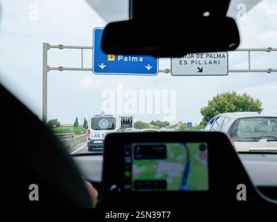 Mallorca, Spain - Jun 28, 2023: A car dashboard displays Apple CarPlay navigation, showing a route to Palma, Mallorca, while driving behind an ambulan Stock Photo