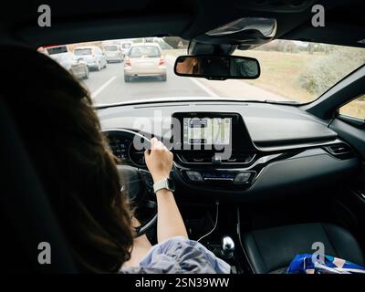 Mallorca, Spain - Jun 28, 2023: A woman navigates through traffic in Mallorca, using a car's infotainment system with CarPlay, driving a modern rental Stock Photo