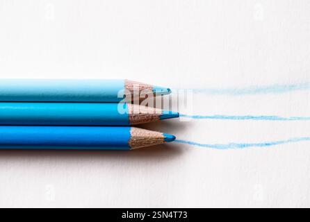 Three colored pencils in shades of blue with lines drawn on white background Stock Photo