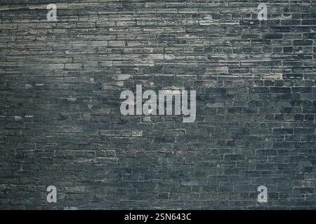 Dark gray brick wall forming a textured background Stock Photo