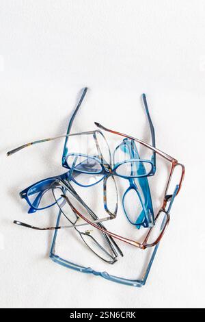 A stack of reading glasses with plastic and metal frames isolated on a white background Stock Photo
