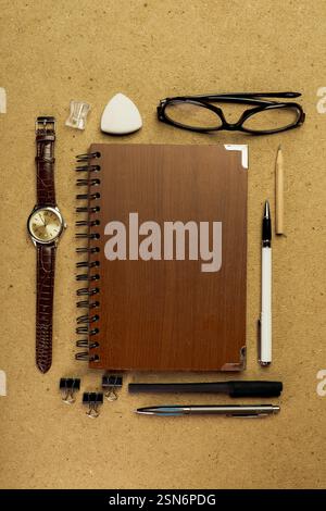 Workspace setup with various stationery items, a notebook, and glasses laid out on a textured background Stock Photo