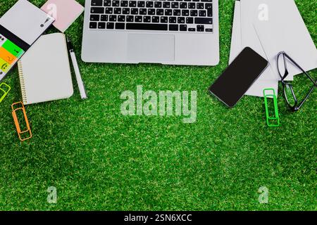 Workspace set up on artificial grass with a laptop, stationery, and a smartphone, perfect for creative activities and remote work Stock Photo