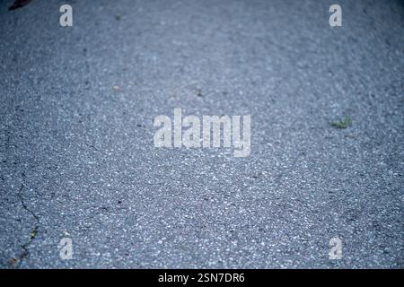 Close-up of a gray asphalt road showing detailed texture and small debris, illustrating urban infrastructure. Stock Photo