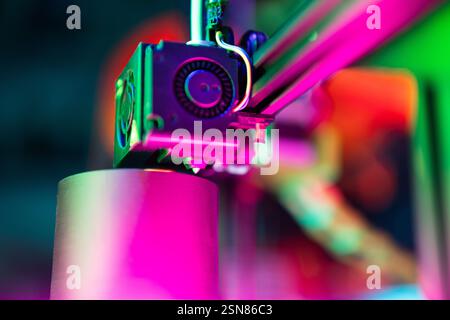 printed 3d object printer arm nozzle close vibrant close-up  extruder, highlighted by neon lighting, representing innovation hobby technology Stock Photo
