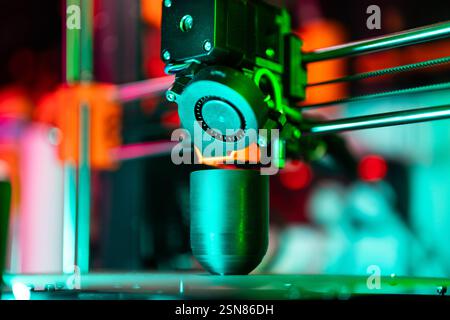A close-up of a 3D printer's extruder in action, captured with vibrant, neon lighting that creates an artistic and futuristic atmosphere. The image sh Stock Photo
