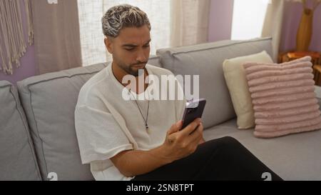 Young man with beard using smartphone in cozy living room Stock Photo