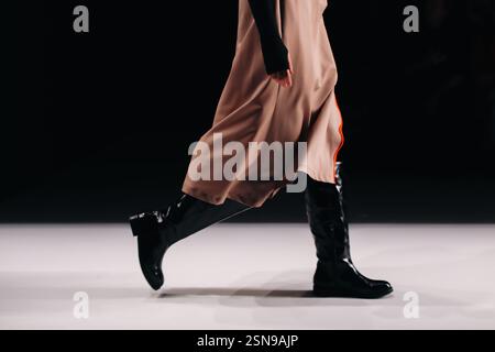 Stylish fashion details of brown silky skirt and black boots, women's fashion cloth concept on black background, copy space Stock Photo
