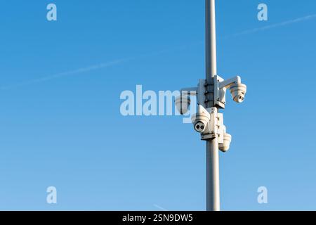 Multiple surveillance cameras in city attached to a tall metal pole for urban monitoring and public safety, blue sky Stock Photo