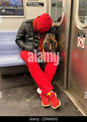 Man in red napping on a New York City subway train. Stock Photo