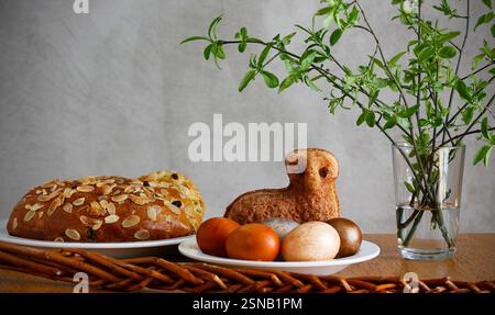 Easter still life containing a small lamb cake, painted eggs, traditional Czech Easter sweet cake called "mazanec", an Easter whip and green twigs Stock Photo