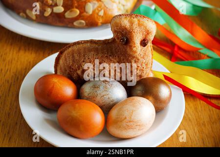 Easter still life containing a small lamb cake, painted eggs, traditional Czech Easter sweet cake called "mazanec" and an Easter whip Stock Photo