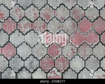 Curvy ornamental outdoor paving stone tiles, dark grey and pink color. Weathered and rusty paving stone in classic ornamental pattern. Pavement outdoo Stock Photo