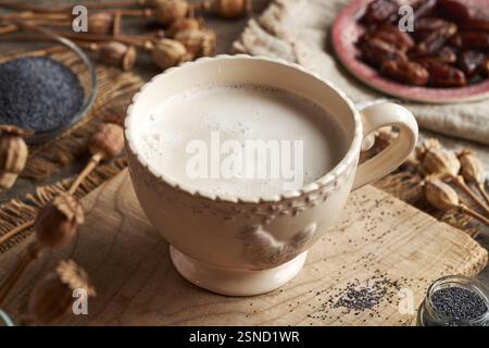 Homemade vegan poppy seed milk sweetened with dates in a cup on a wooden table Stock Photo