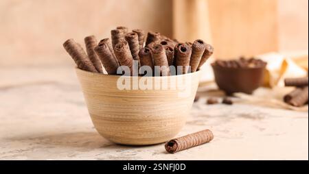 Bowl of delicious chocolate wafer rolls on table Stock Photo