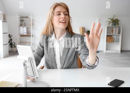 Young businesswoman with tablet computer using virtual screen at table in office Stock Photo