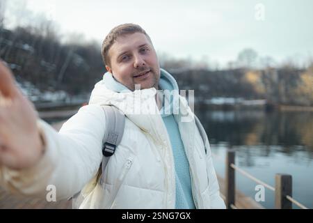 Young happy man takes selfie photo during his awesome hiking trek somewhere in forest, walking by the lake Stock Photo