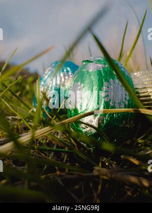 Close up low angle view of tin foil covered chocolate eater eggs in grass outdoors Stock Photo