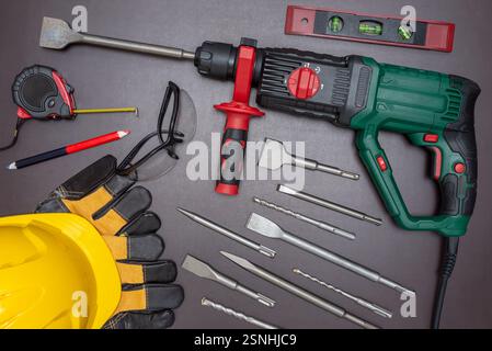 Hammer drill with a set of accessories and protective equipment on a working table. Stock Photo