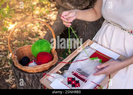 Woman weaver's hands using a weaving needle on a hand loom. Selective focus. Stock Photo