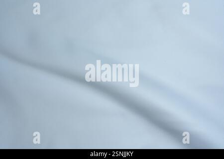 Close-up of light blue fabric with gentle folds and smooth texture, creating a minimalistic background. Stock Photo