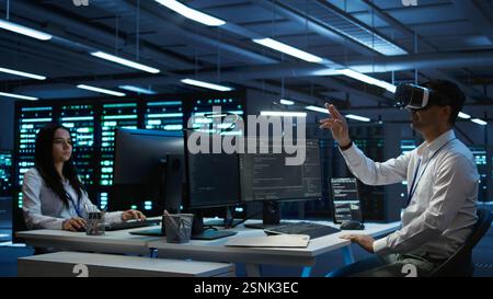 Data center admin responsible for installation of networking systems wearing high tech VR headset. IT worker doing maintenance on server farm gear using virtual reality technology, camera B Stock Photo
