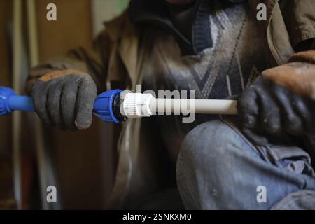 Close-up of gloved hands adjusting a pipe fitting Stock Photo
