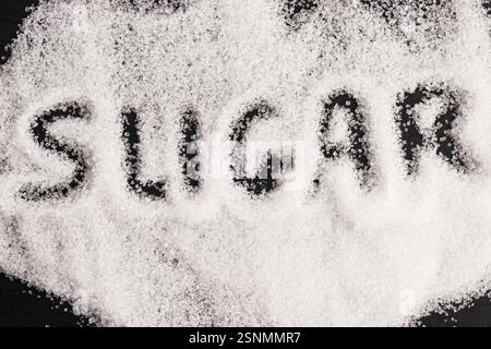 The word sugar written into a pile of white granulated sugar Stock Photo
