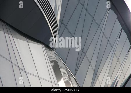 Germany, Munich. A close-up view reveals a modern skyscraper's facade, its surface a smooth expanse of reflective glass windows. This curtain wall con Stock Photo