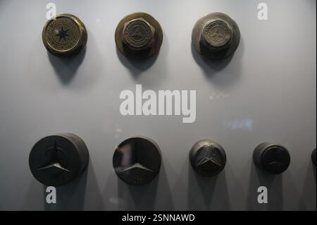 A scattering of nuts and bolts in various sizes rests on a white background. The fasteners appear well-used, their metallic surfaces worn to a dull sh Stock Photo